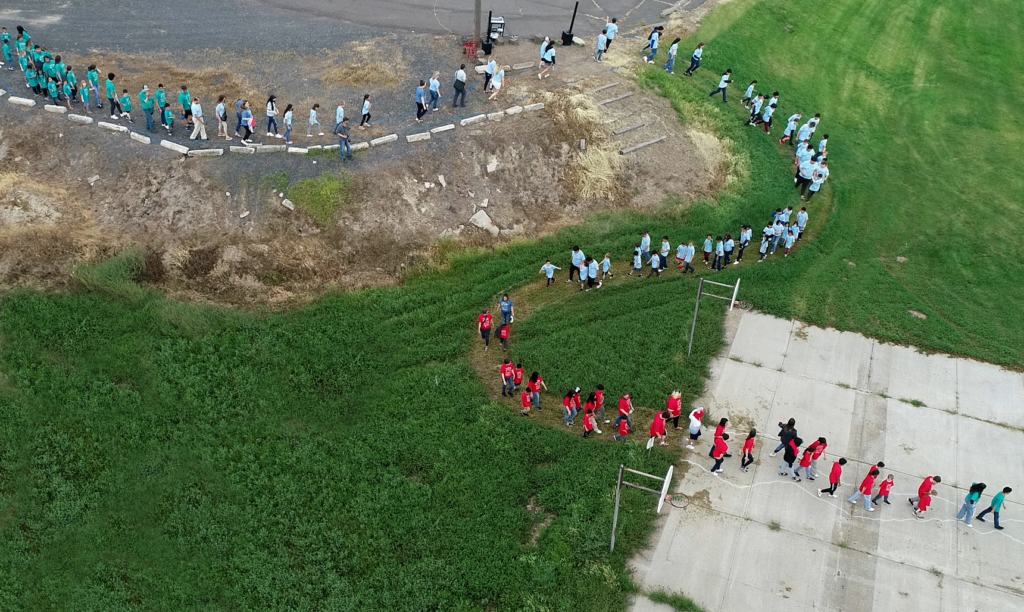 Photo of students forming a "human river" through the grass.