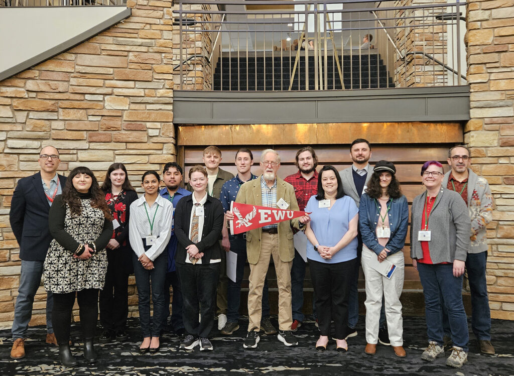 Group photo with students and faculty. Professor Bill Youngs is holding an EWU banner.