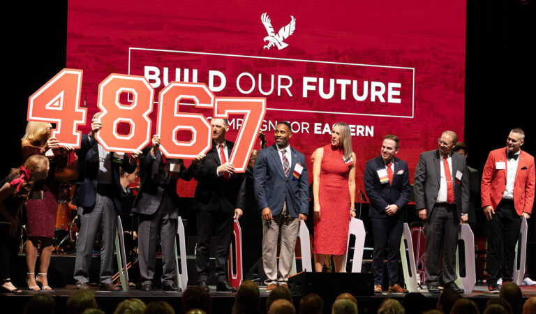 People holding up a sign that says 4867 for the amount of scholarships given.