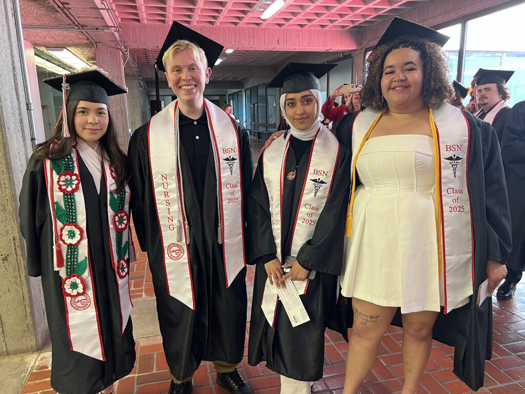 Photo of four nursing students wearing caps and gowns.