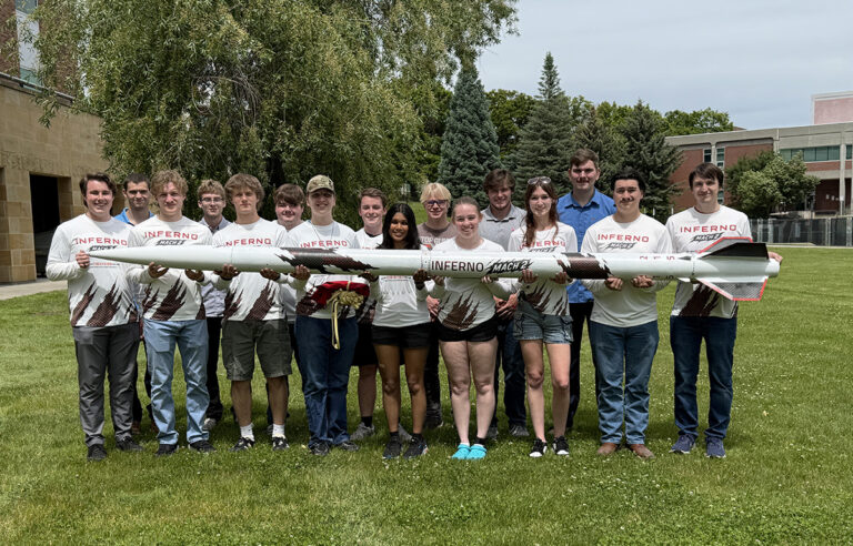 Student rocketeers in a line holding up the rocket.