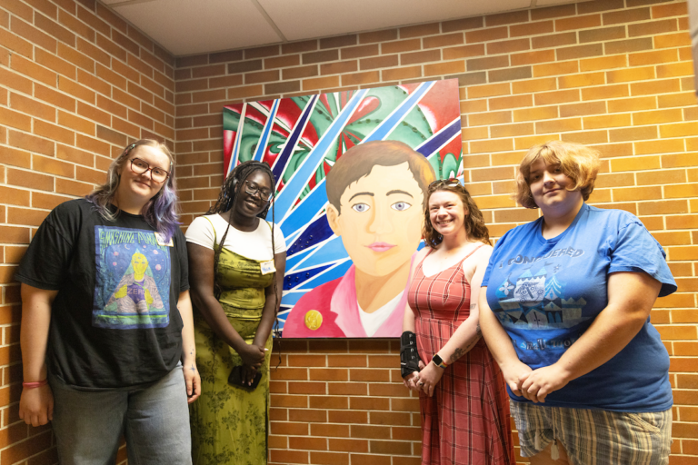 Photo of four students with mural.
