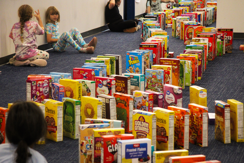 Kids set up boxes of cereal domino-style in their school.