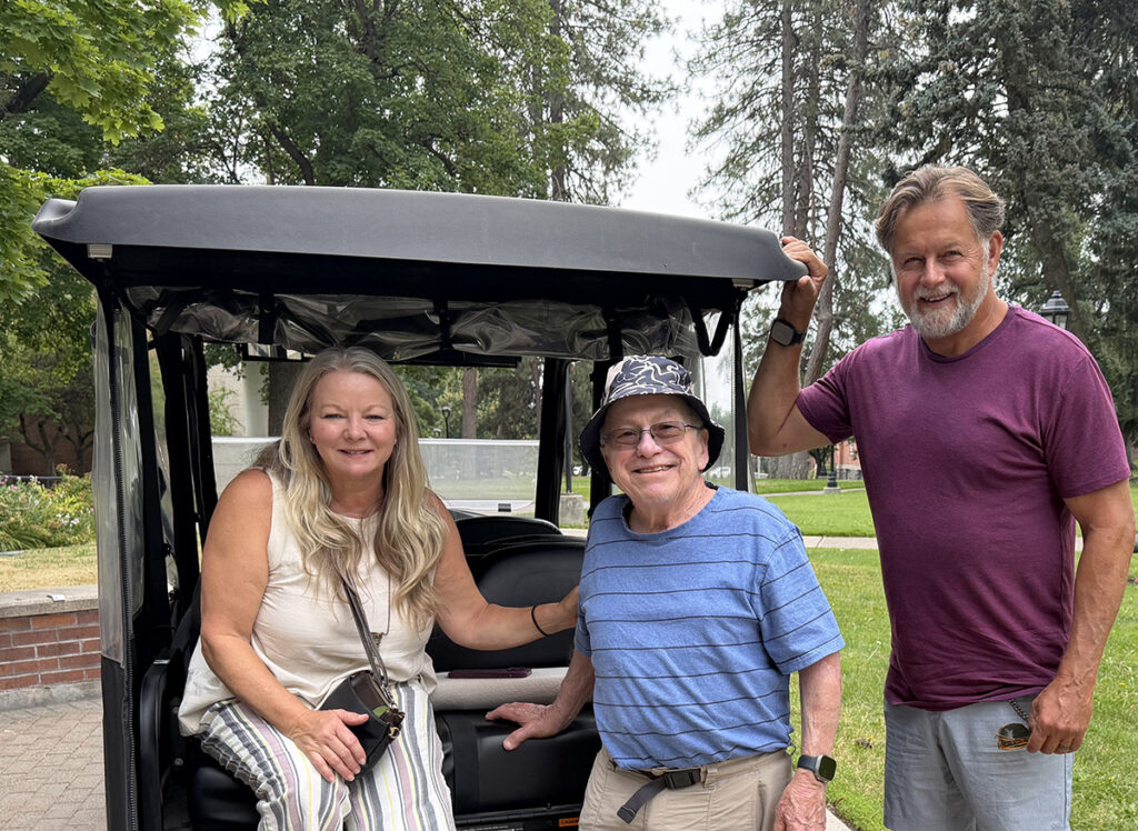 Lisa Fairburn sits in the back of an EWU golf cart. Her brother, Bill Beneke, and husband, Mike Fairburn are on the left.